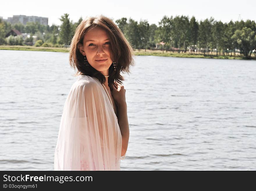 Beautiful girl in a pink dress on shore