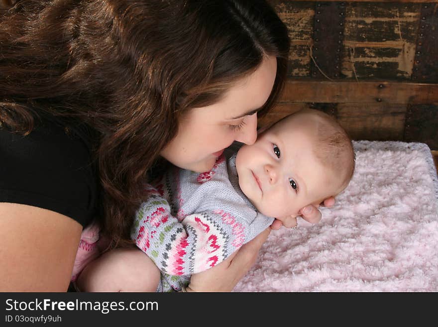 Brunette mother lovingly holding her baby girl. Brunette mother lovingly holding her baby girl