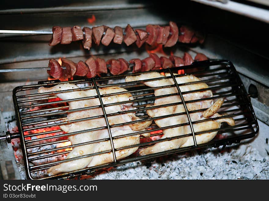 Grilled chicken and kebab getting ready on charcoal fire