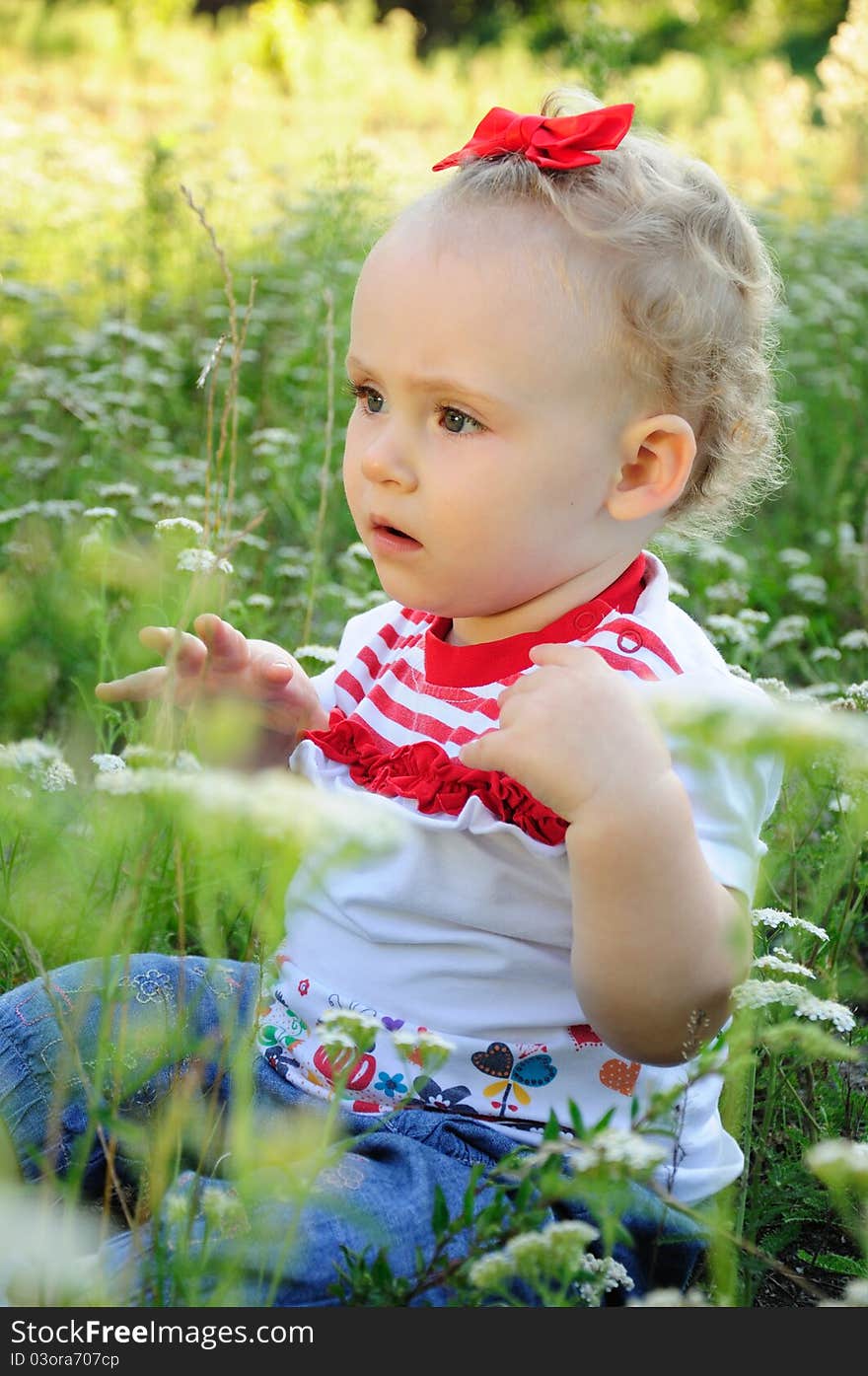 Baby With Red Bow On The Meadow