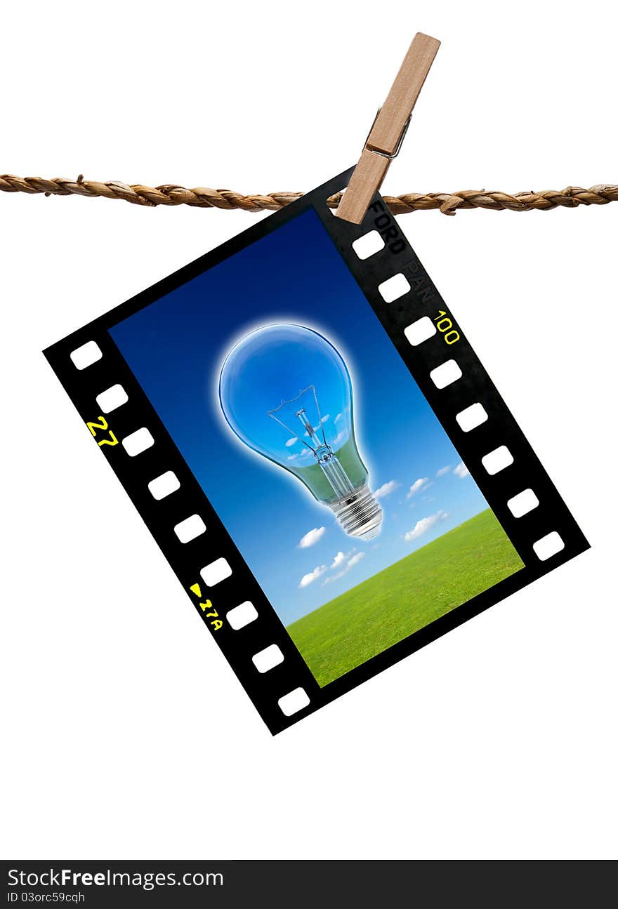 The image blub lamp and grass meadow and blue sky in color transparency films hang on the rope cliped with wooden clip path. The image blub lamp and grass meadow and blue sky in color transparency films hang on the rope cliped with wooden clip path