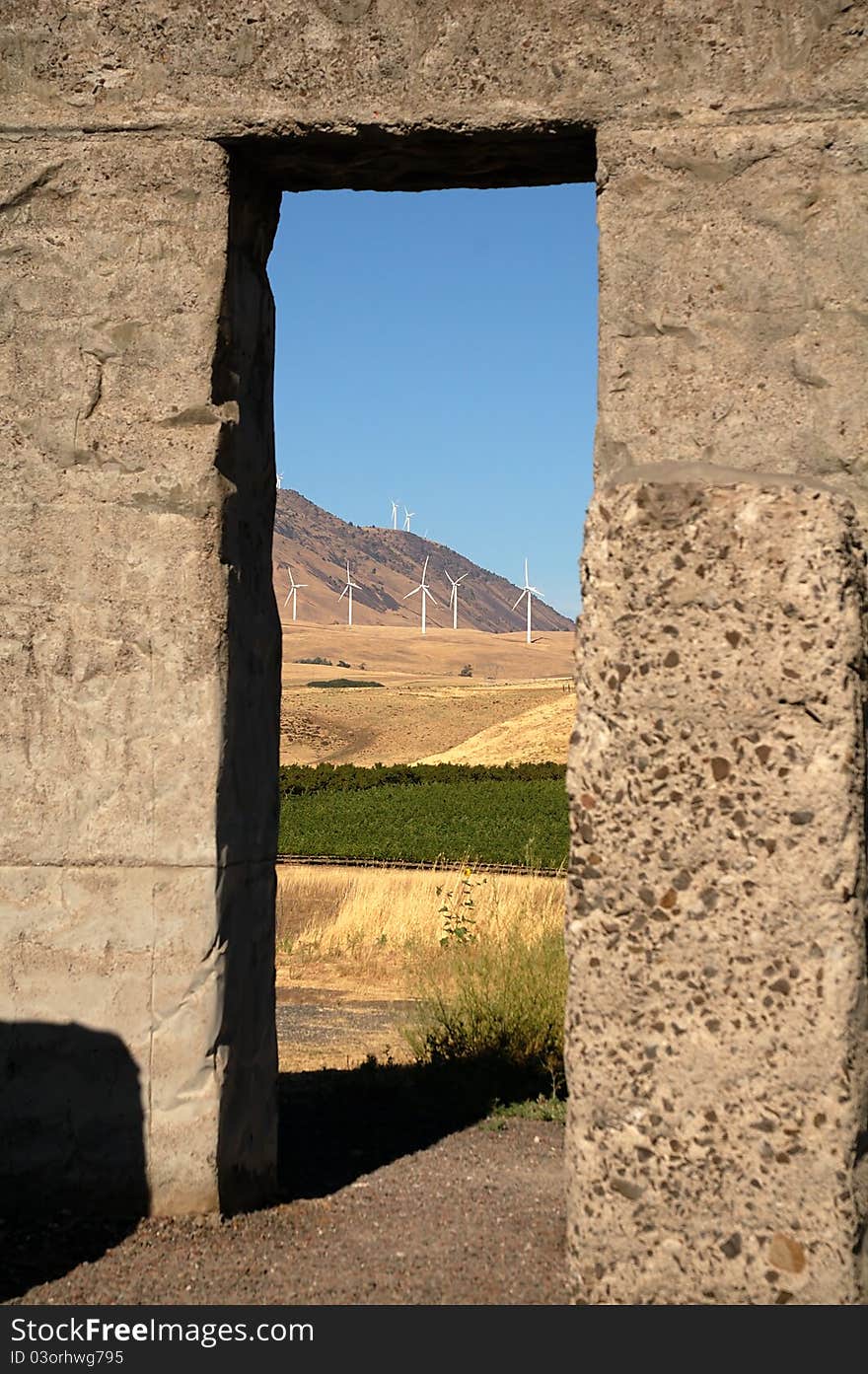 Wind turbines in the background as seen through an opening of an old stone structure. Wind turbines in the background as seen through an opening of an old stone structure.