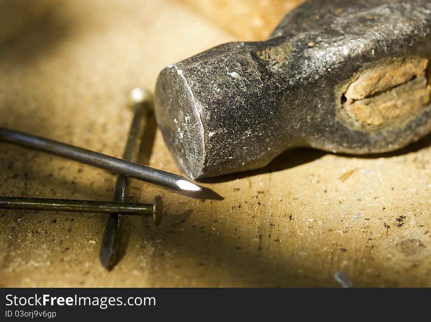 A hammer laying next to nails with selective focus and selective light. A hammer laying next to nails with selective focus and selective light.