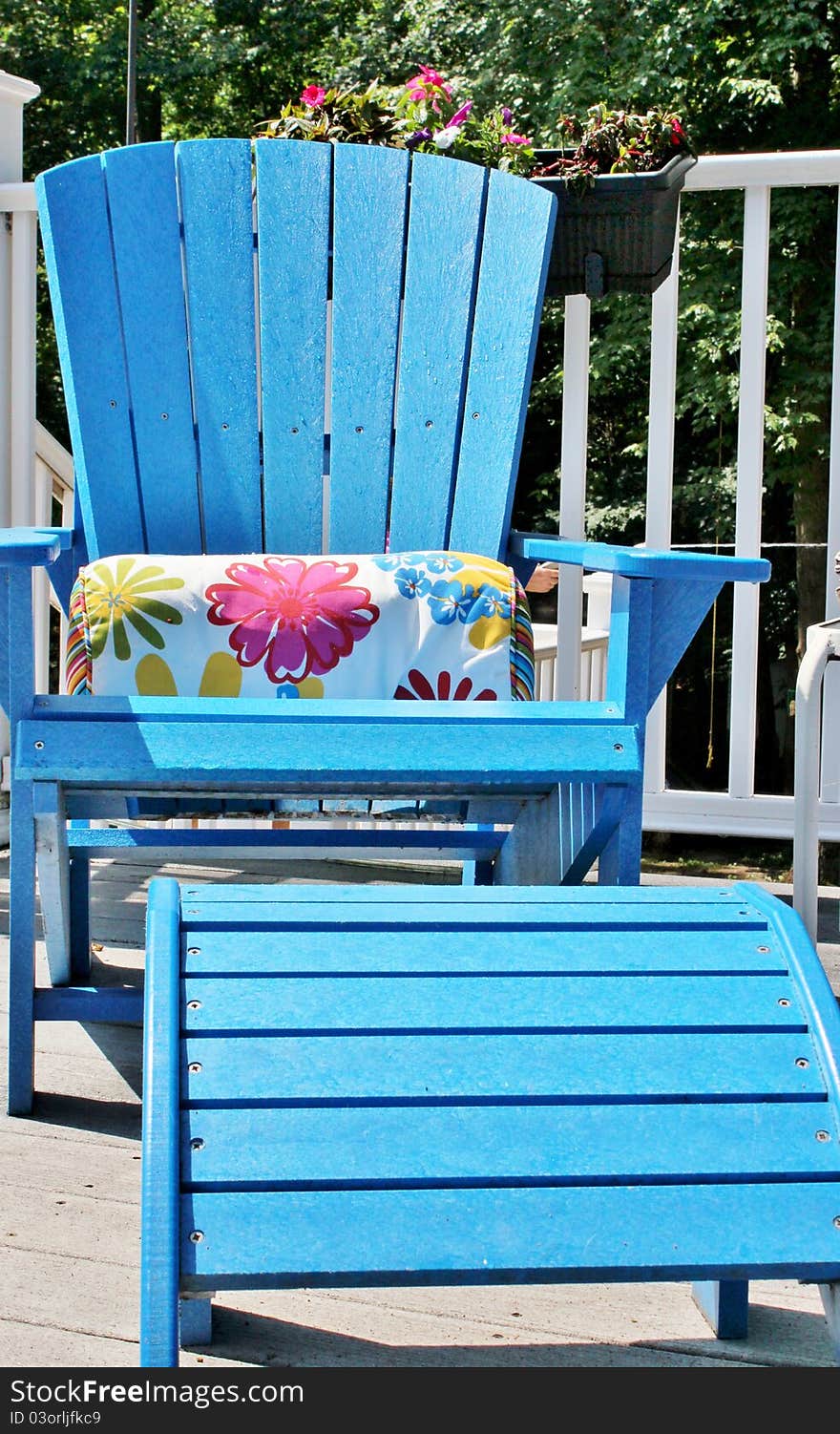 A blue Adirondack chair with foot rest on a white outdoor deck