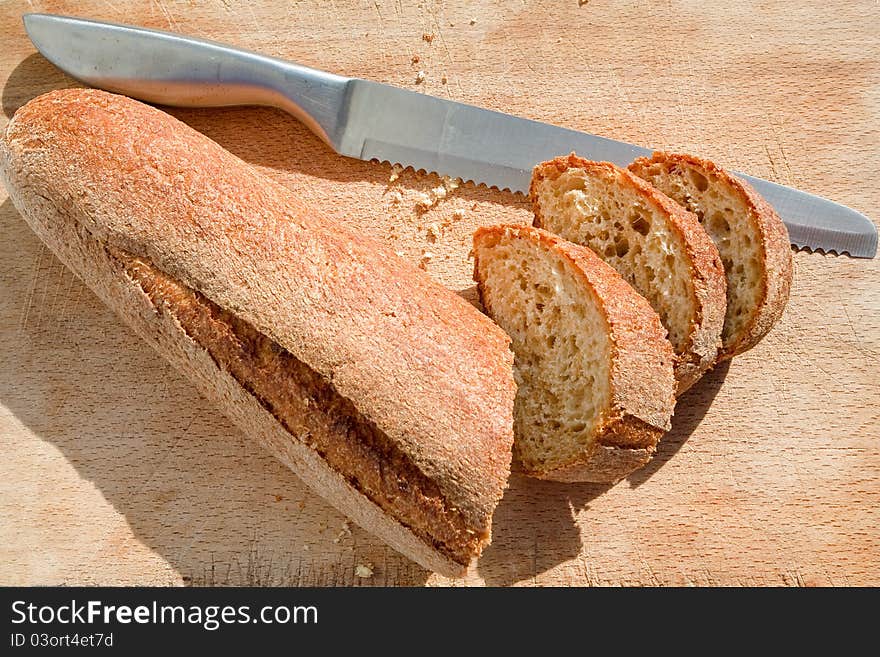 Bread knife and bread on wooden board