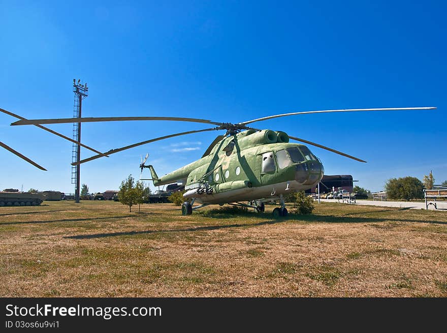 Old Russian helicopter on the grass. Against the background of blue sky.