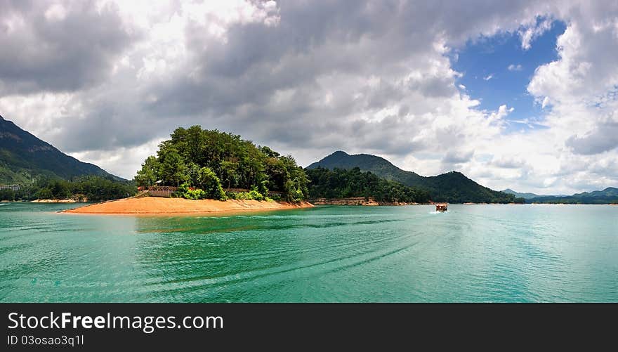 Little boat in the green river with cloudy sky.