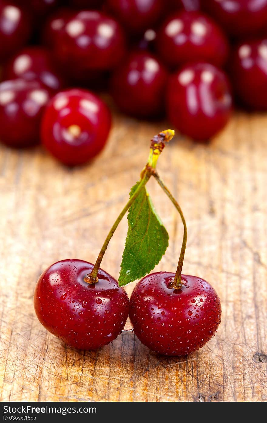 Wet cherries on wooden table with fruits on the background. Wet cherries on wooden table with fruits on the background