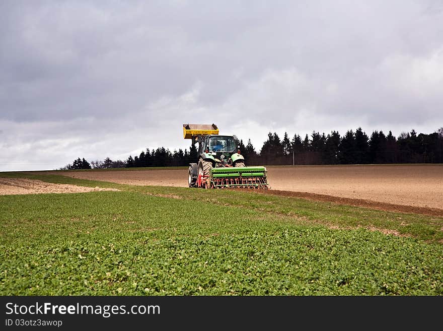 Tractor plowing the acre under dark clouds. Tractor plowing the acre under dark clouds