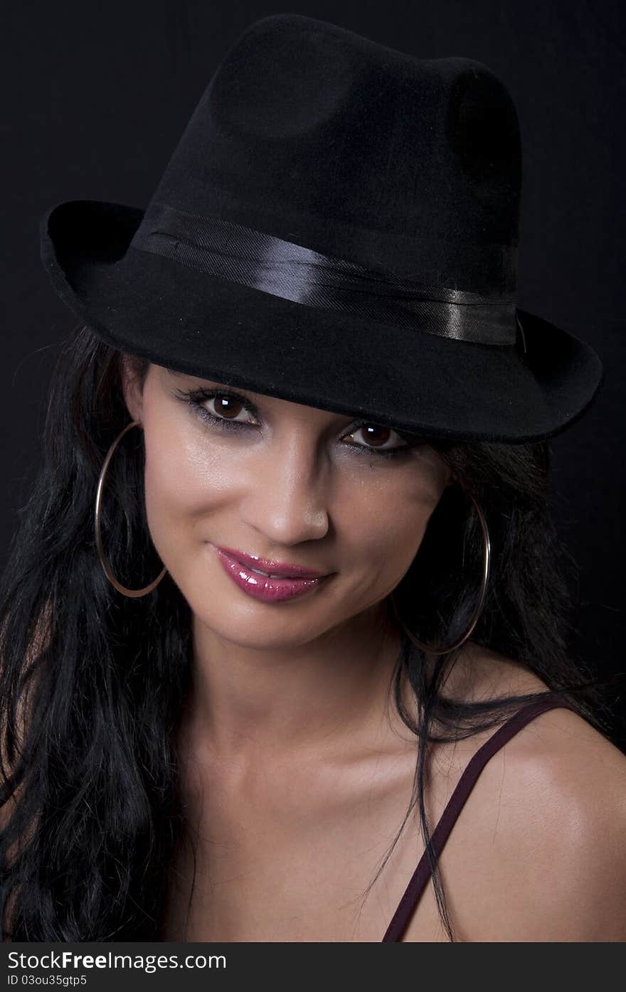 Beautiful brunette with black hat with black background