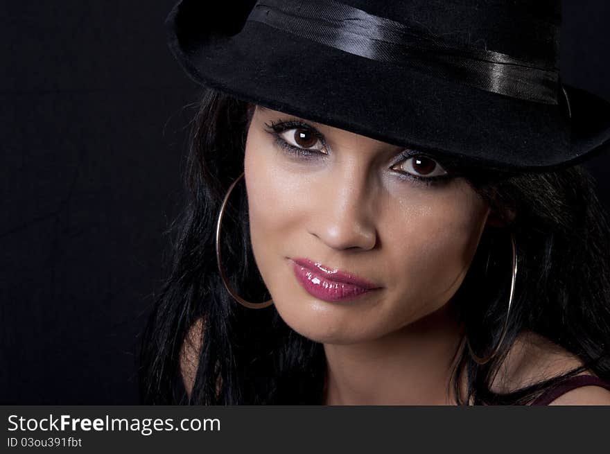 Beautiful brunette with black hat with black background