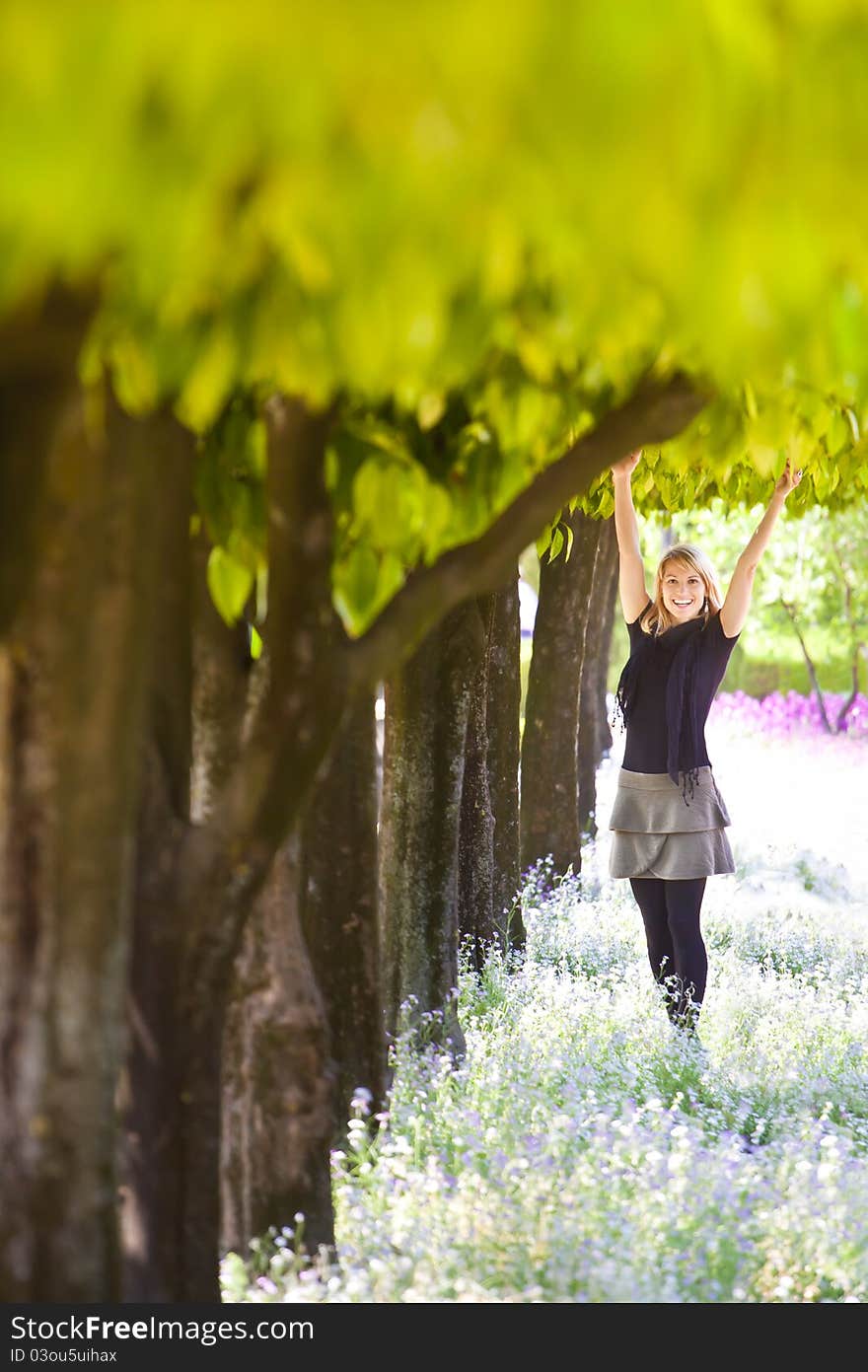 Young lady smiling with arms raised to the crown, enjoying the fresh air in green park. Young lady smiling with arms raised to the crown, enjoying the fresh air in green park.