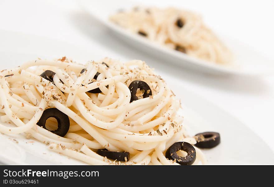 Spaghetti with black olives on a white background