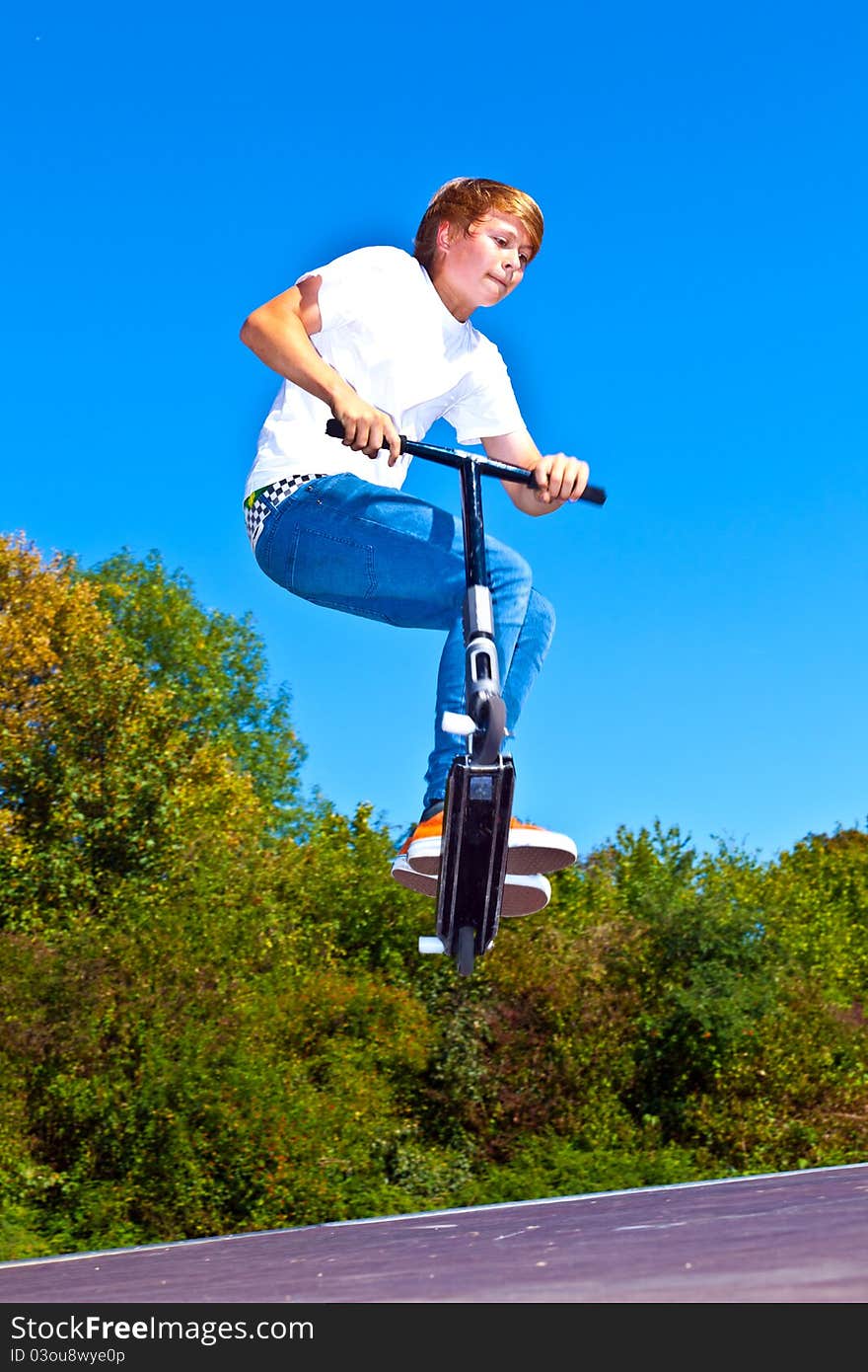 Boy jumping with his scooter at the skatepark