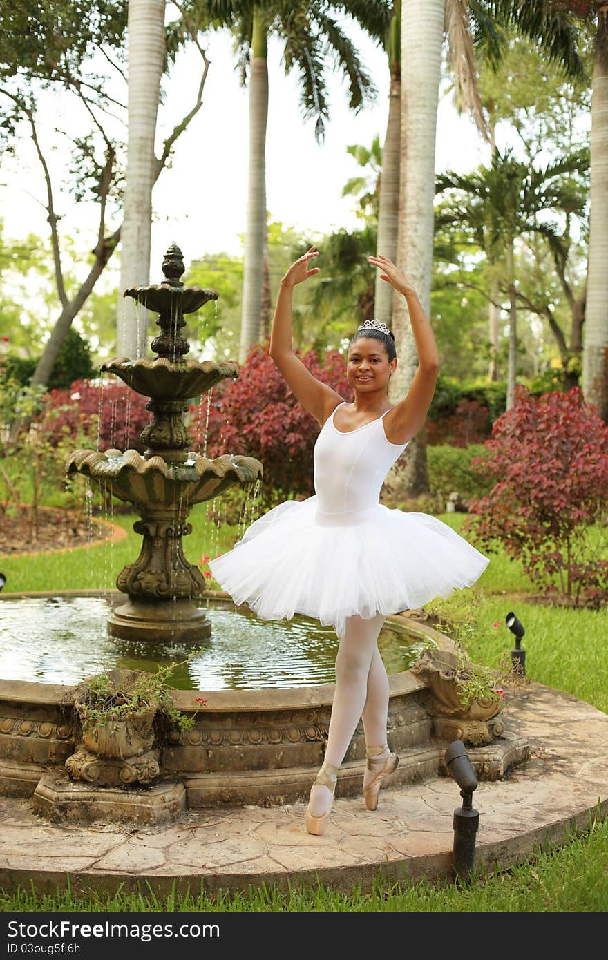 Image of a young ballerina posing in a garden by a fountain. Image of a young ballerina posing in a garden by a fountain