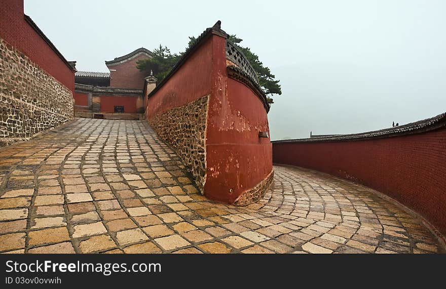 A winding passage flanked by red walls leading to the mount wutai temple in china. A winding passage flanked by red walls leading to the mount wutai temple in china.