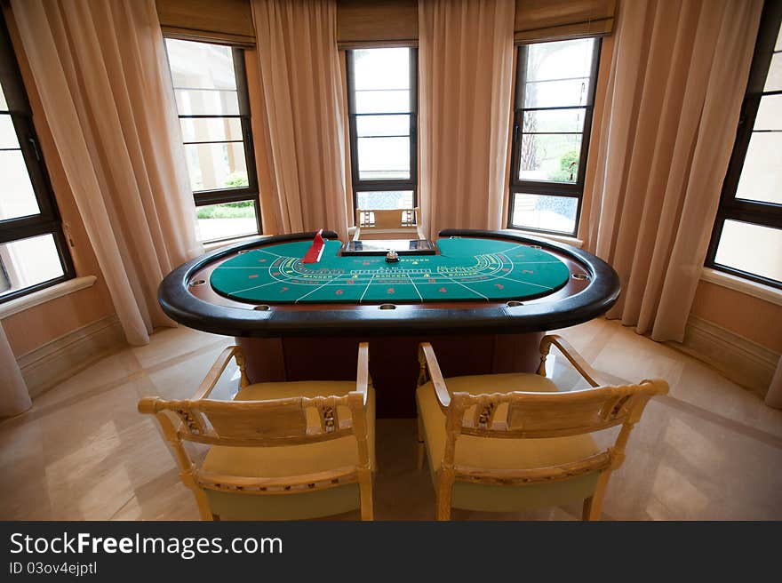 A Gambling table placed in the front of big windows.