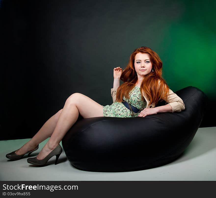 Studio shot of beautiful red haired woman sitting on the chair