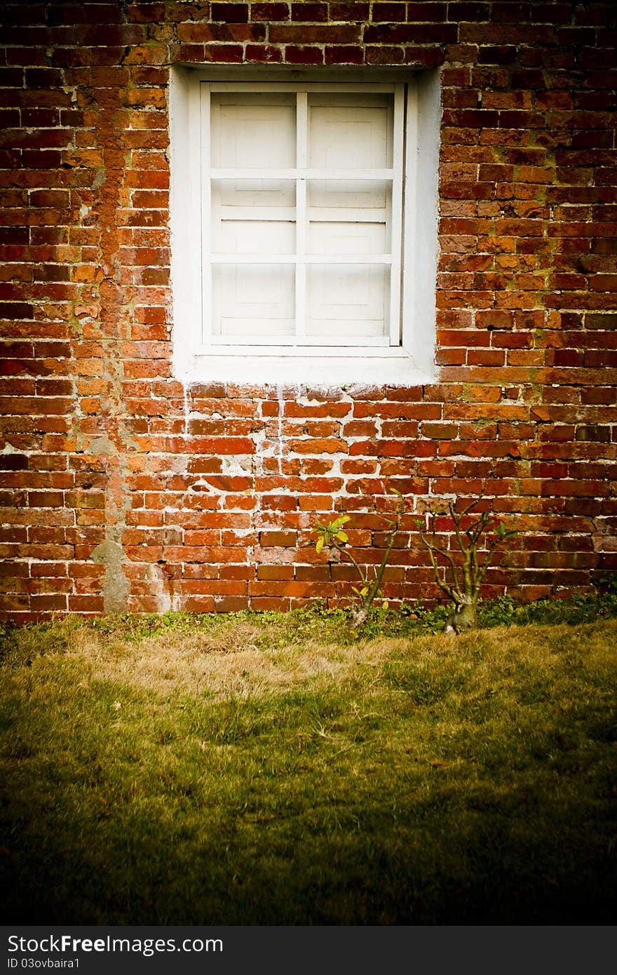 Red brick Wall with white window and grass