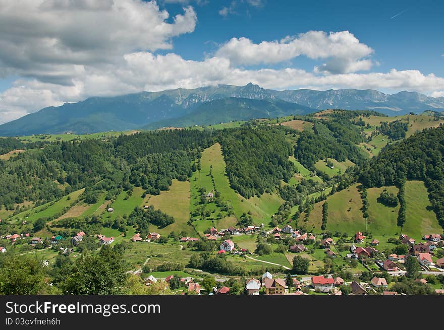 View from above of a village in the Romanian countryside. Mountains and cloudscape in the background. View from above of a village in the Romanian countryside. Mountains and cloudscape in the background