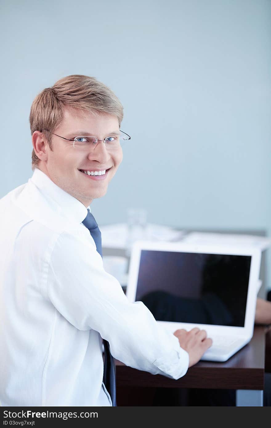 A young man with a laptop in the office. A young man with a laptop in the office