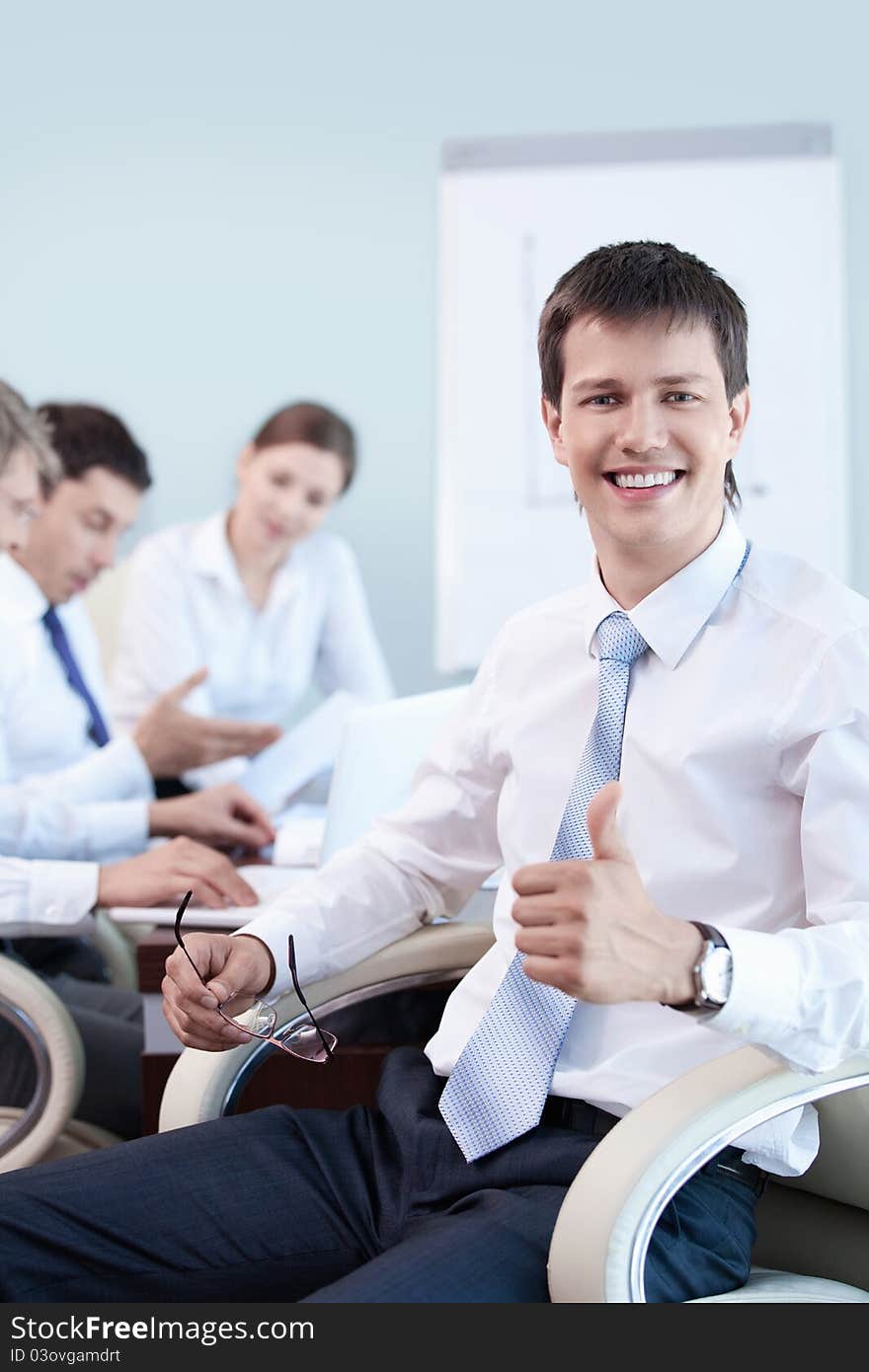 An attractive young man with his thumb up in the office. An attractive young man with his thumb up in the office