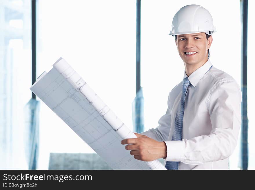 A man in a helmet with a plan for construction. A man in a helmet with a plan for construction