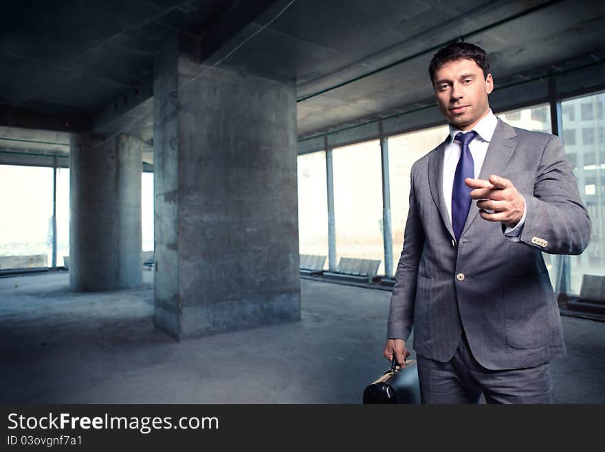 A man in a suit with a briefcase at a construction site. A man in a suit with a briefcase at a construction site