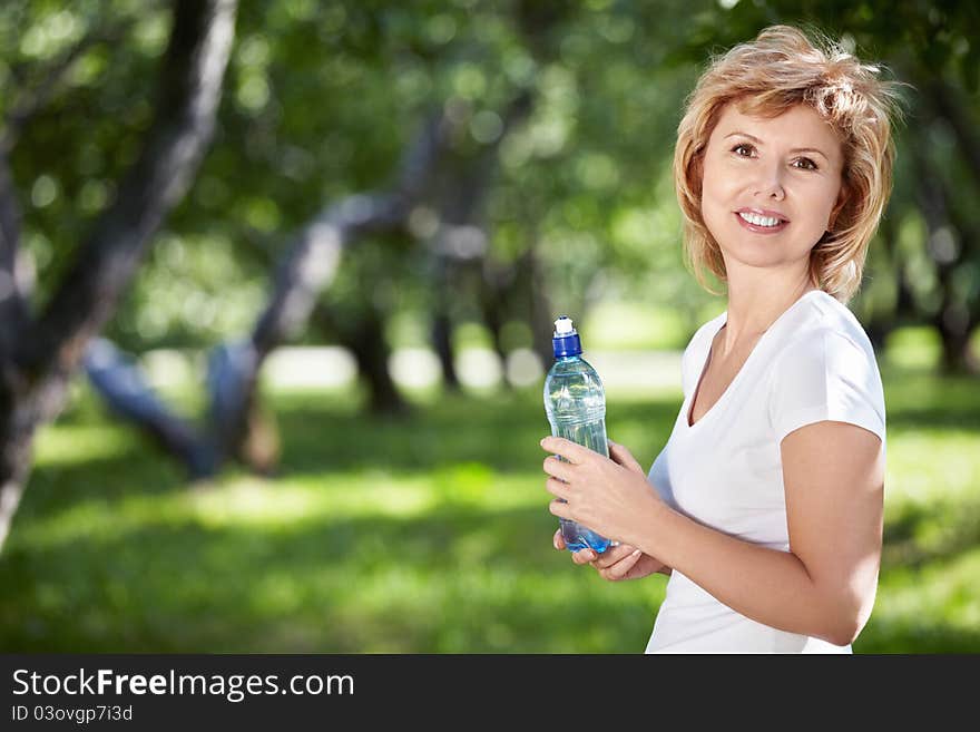 Mature woman with a bottle of water in the park. Mature woman with a bottle of water in the park