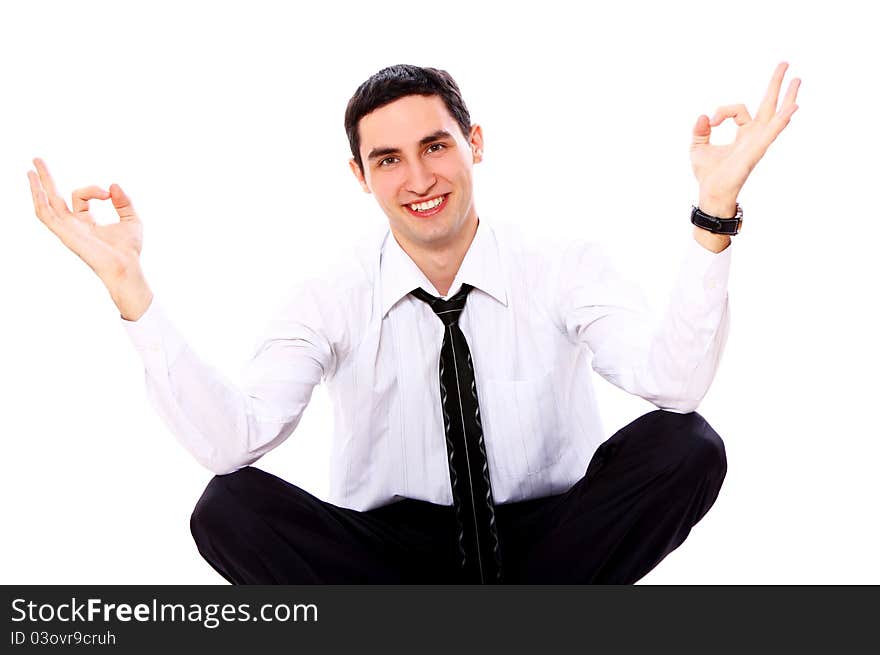 Smiling businessman in yoga pose showing OK sign isolated over white