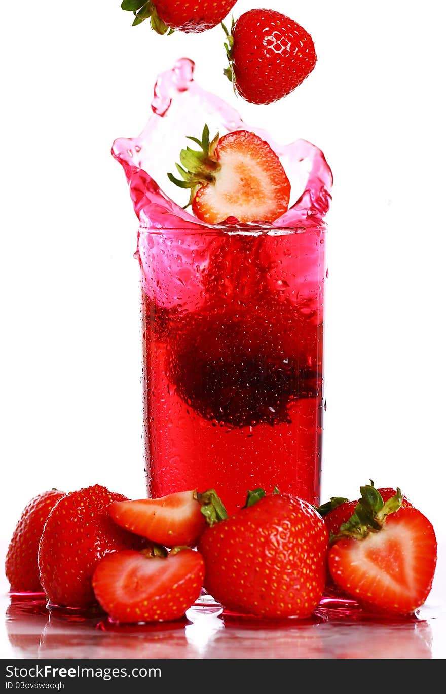 Strawberry falling into the glass with drink and makes big splashes