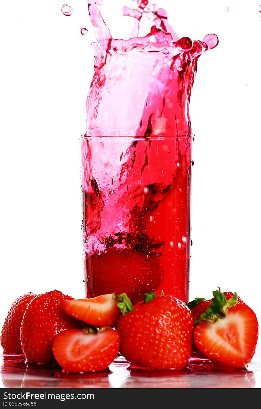 Strawberry falling into the glass with drink and makes big splashes