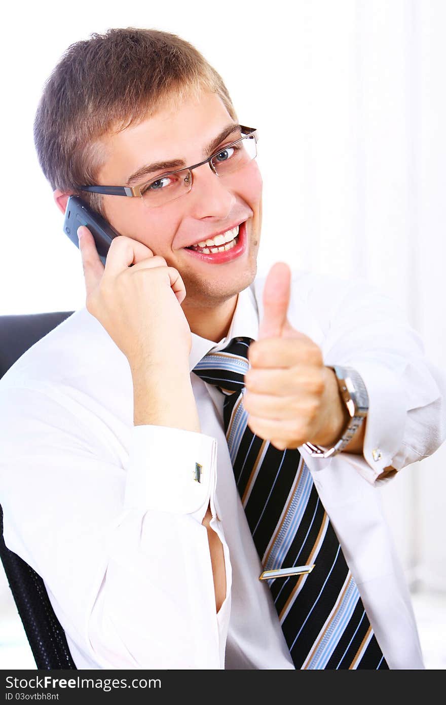 Young Businessman shows OK sign while calling by phone in his office