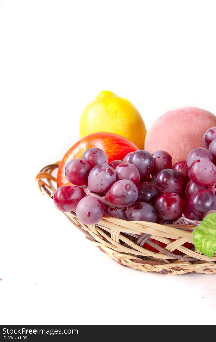 Apple, grapes, lemon and peach in a basket. Apple, grapes, lemon and peach in a basket