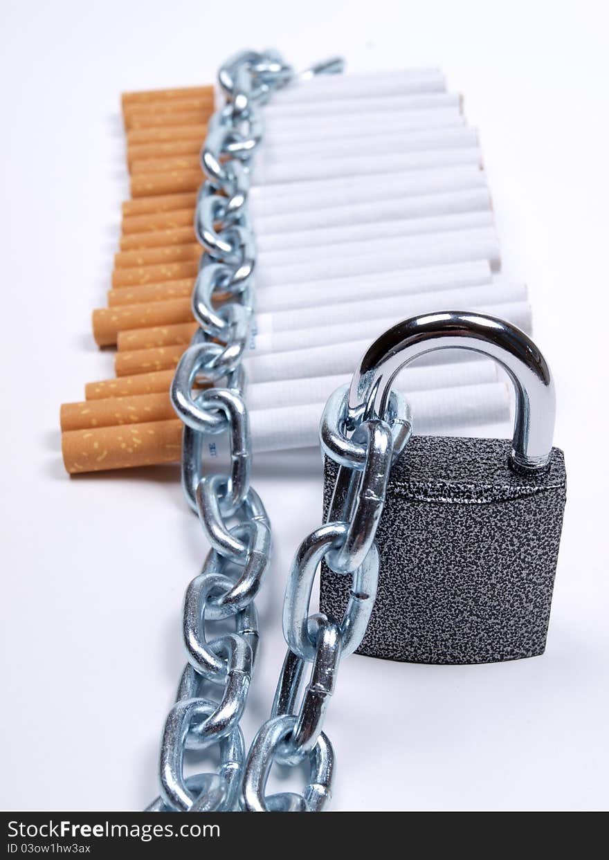 Color photo of pile of cigarettes and a padlock with chain. Color photo of pile of cigarettes and a padlock with chain