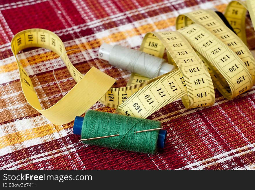 Four coils with strings and a centimetric tape on a checkered fabric. Four coils with strings and a centimetric tape on a checkered fabric