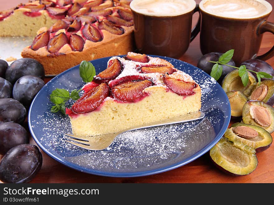 Plum pie, coffee and plums deocrated with mint on a wooden background. Plum pie, coffee and plums deocrated with mint on a wooden background