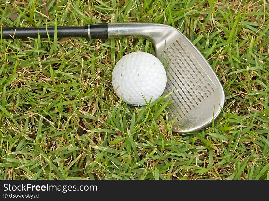 Golf club and one ball on grass