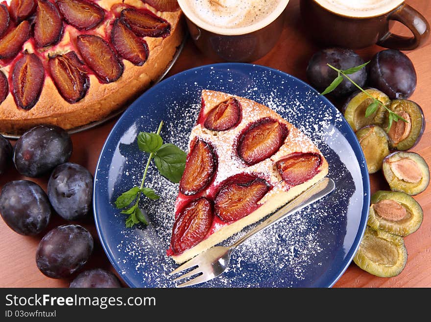 Plum pie, coffee and plums decorated with mint on a wooden background