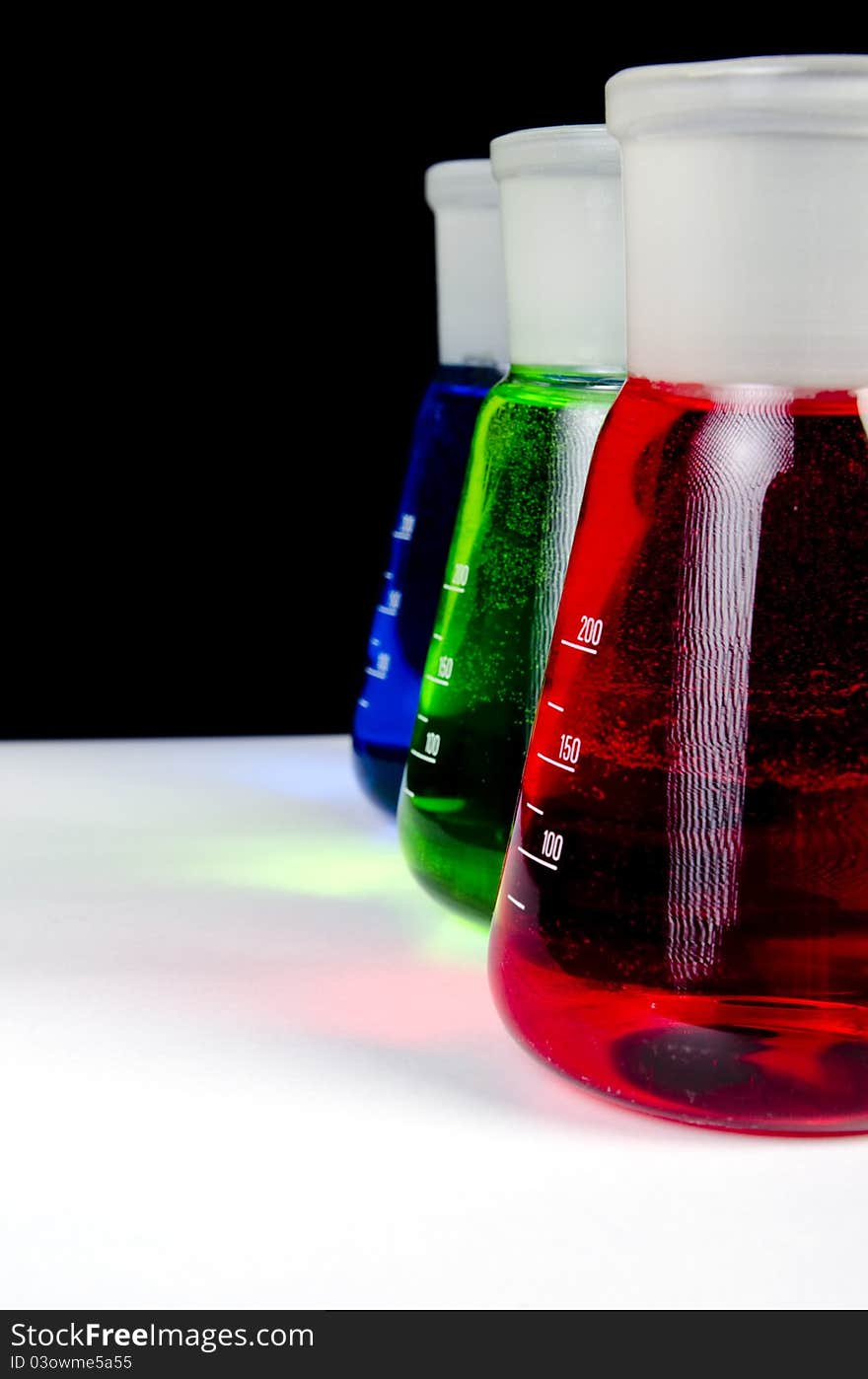 3 colors chemicals in laboratory glassware in a row - Close up on black background. 3 colors chemicals in laboratory glassware in a row - Close up on black background