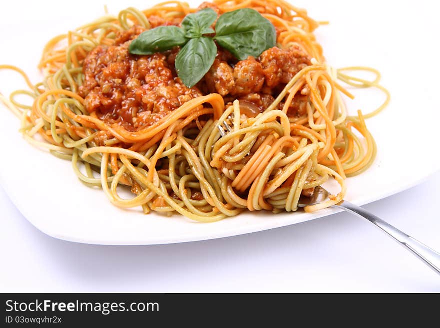 Spaghetti bolognese on a plate being eaten with a fork