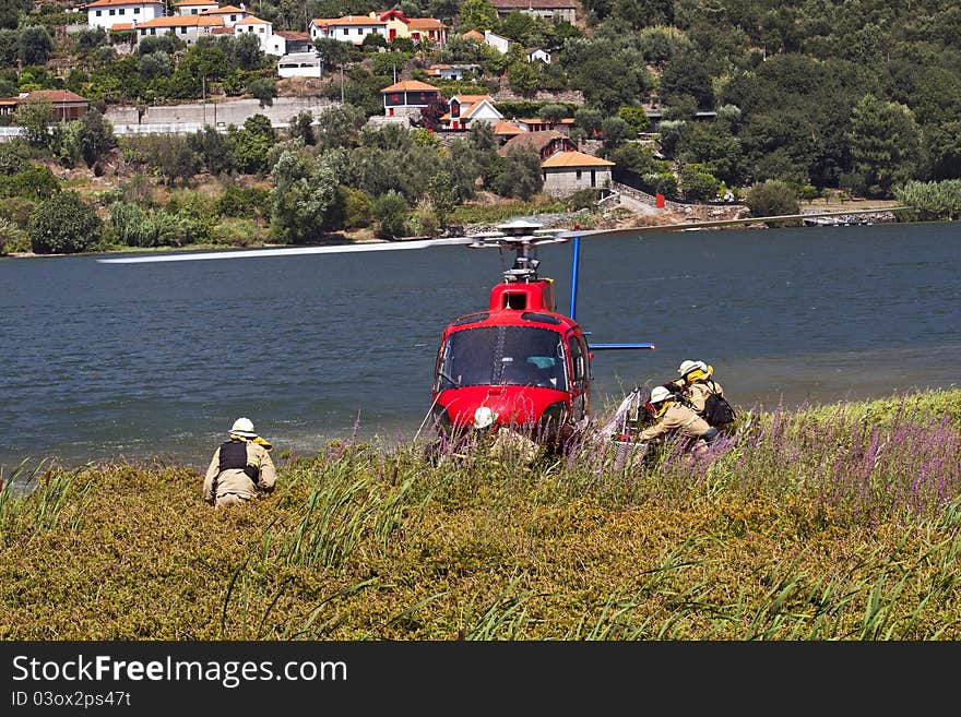 Crew of firefighters working on the helicopter stopped on the banks of the River Douro. Crew of firefighters working on the helicopter stopped on the banks of the River Douro