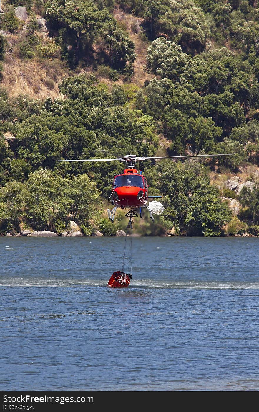 Firefighting helicopter collecting water in the Douro river to extinguish the forest fire. Firefighting helicopter collecting water in the Douro river to extinguish the forest fire