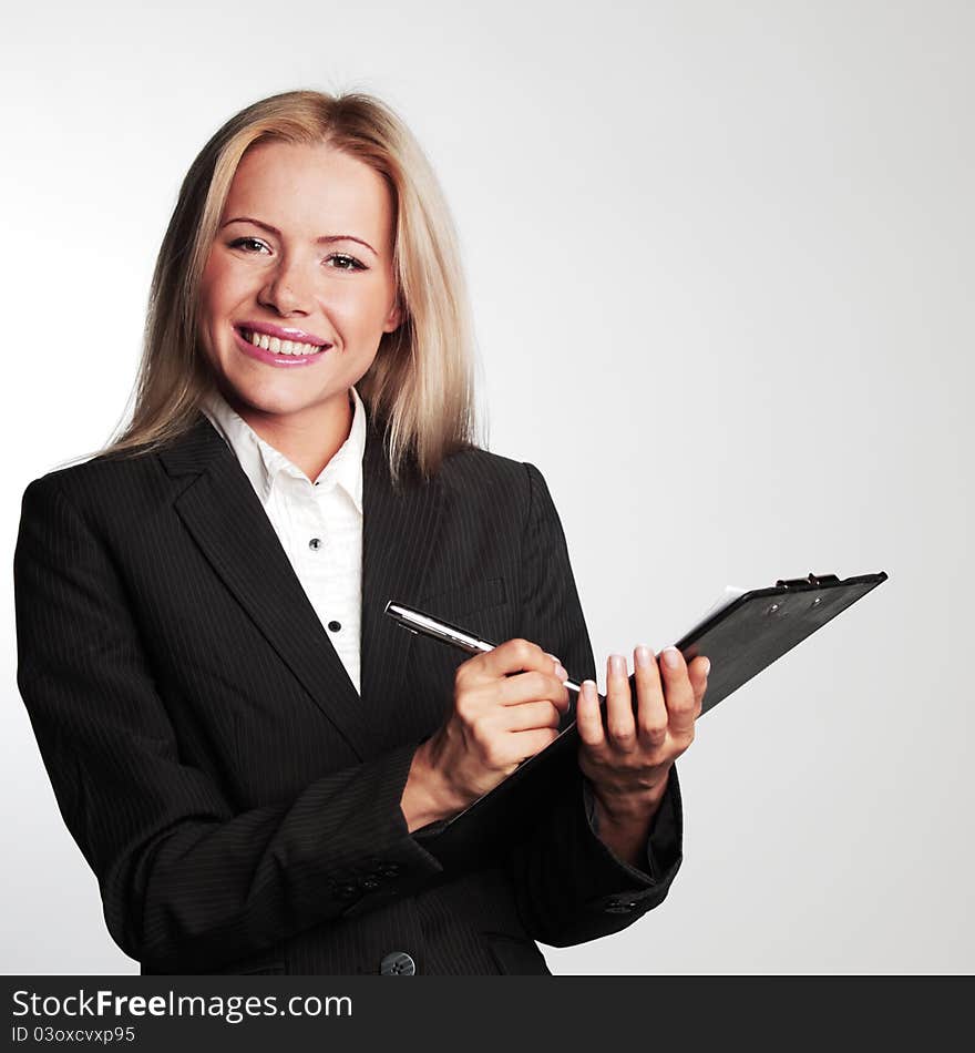 Business woman writing in notebook on a gray background