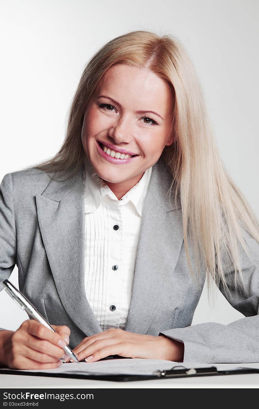 Business woman writing in notebook on a gray background