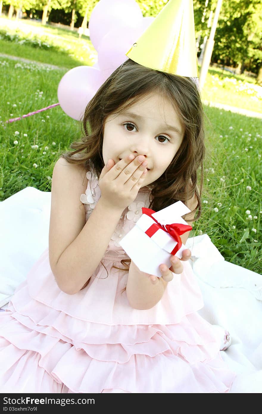 Little girl outdoors celebrating birthday is happy and holding a gift box. Little girl outdoors celebrating birthday is happy and holding a gift box.