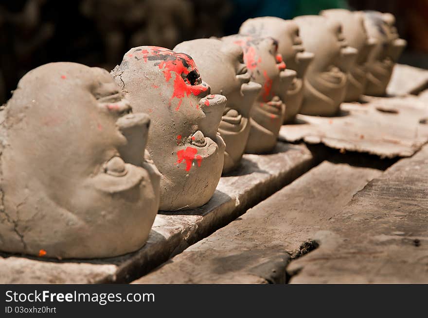 Clay heads of Goddesses and demons in a row are kept for drying in sunlight. Clay heads of Goddesses and demons in a row are kept for drying in sunlight