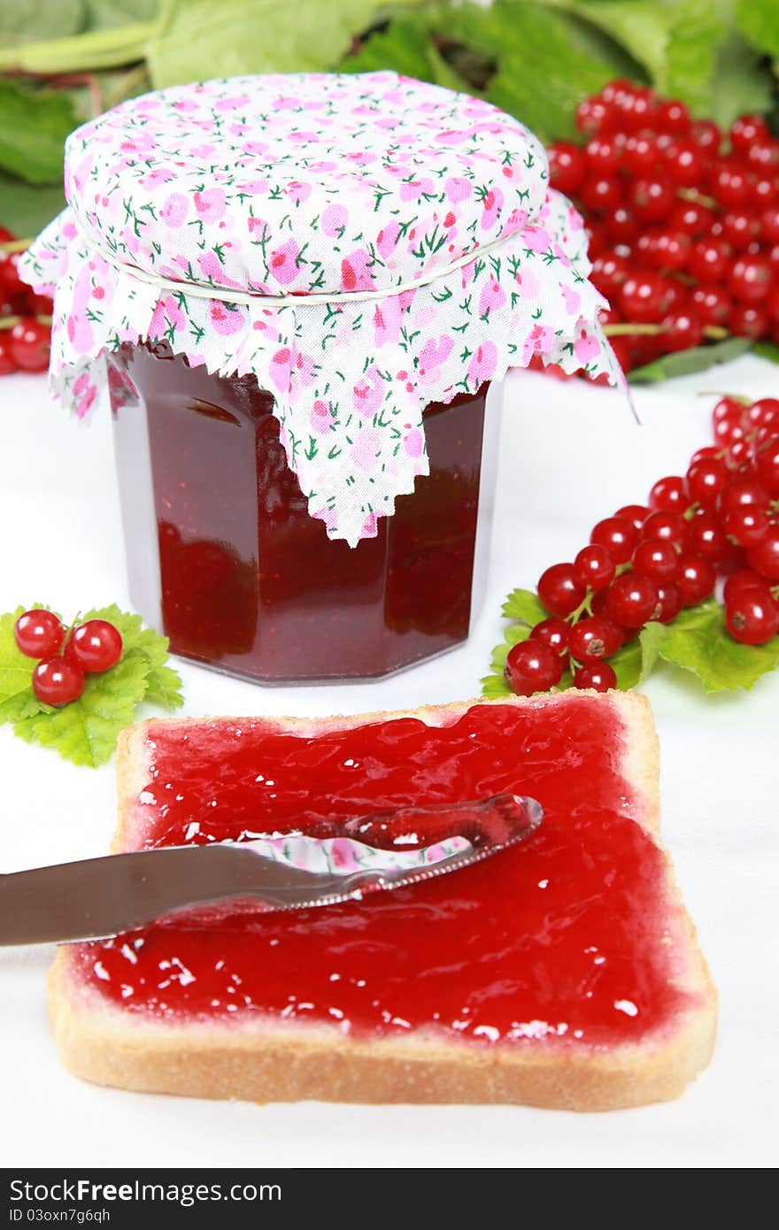 One glass of homemade red currant jam with fresh fruits, leaves and toast