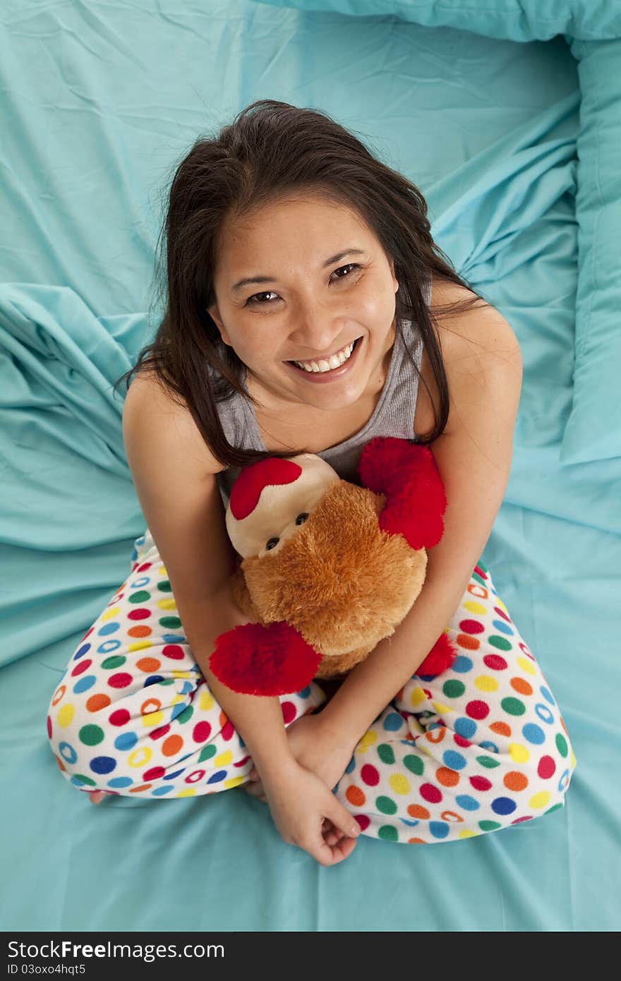 A woman looking up while she is in bed holding on to her stuffed animal. A woman looking up while she is in bed holding on to her stuffed animal