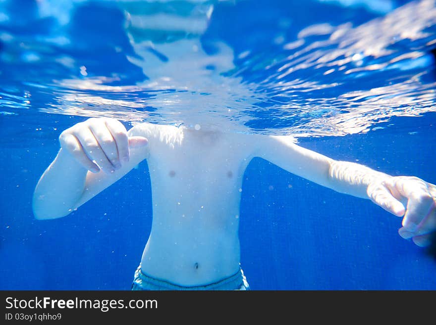 A young boy swimming in a clear pool. A young boy swimming in a clear pool